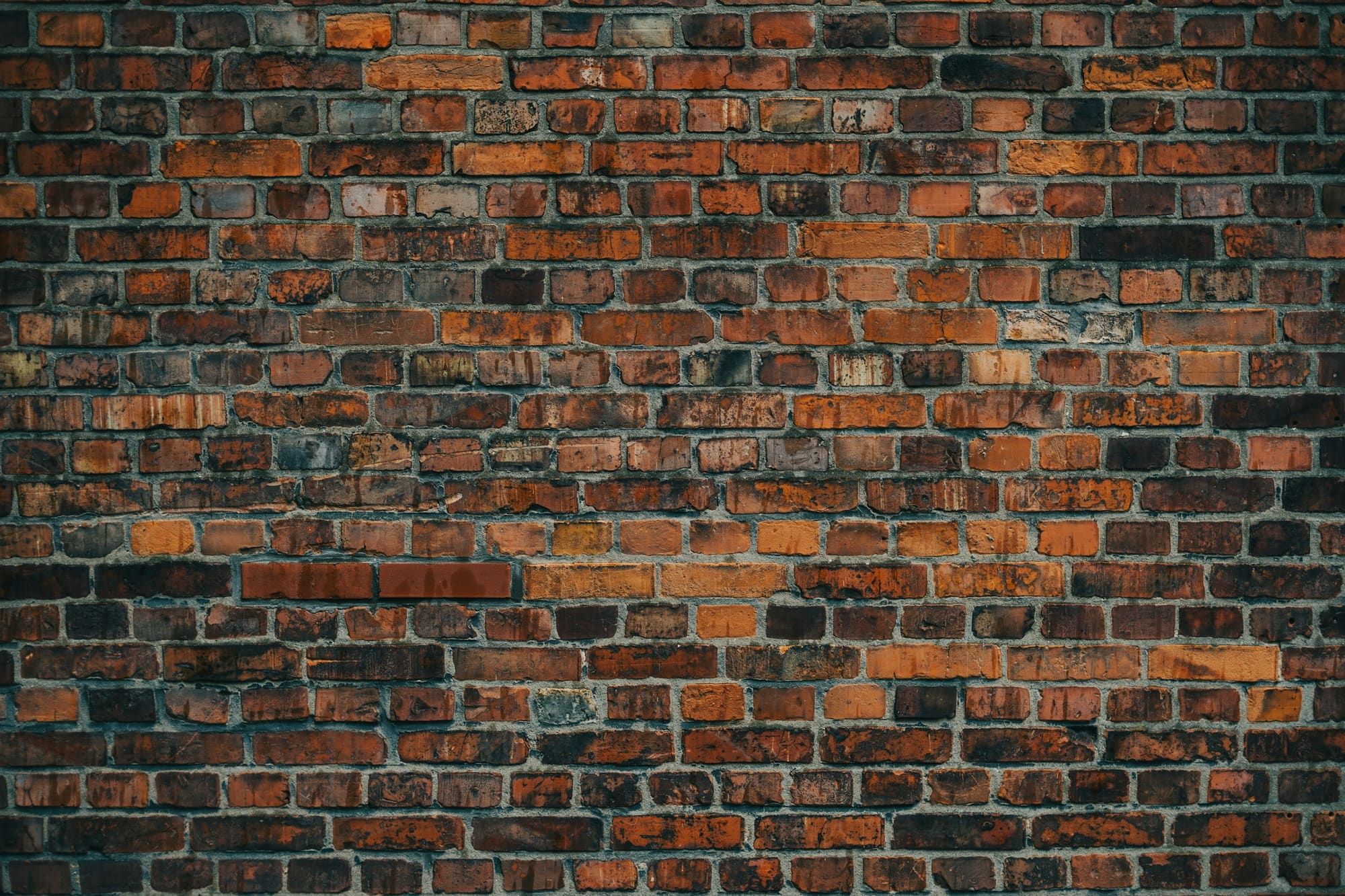 Weathered dark red and orange brick wall in running bond